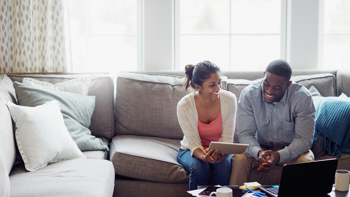 A happy couple reviewing paperwork together in their living room with a laptop on the coffee table