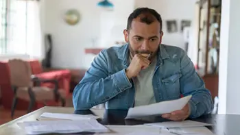 A man deep in thought while reading paperwork