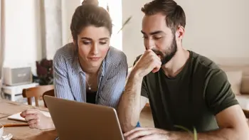 A couple carefully looking at a laptop screen