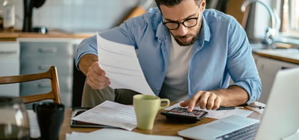 A man using a calculator while reviewing bills