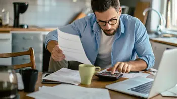 A man using a calculator while reviewing bills