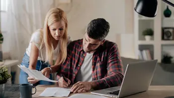 A couple carefully reviewing and signing paperwork